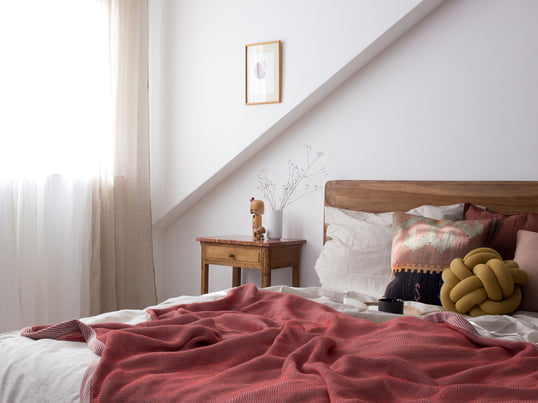 Pepper from heimatbaum.com shows us how she decorated her bedroom with the Ripple blanket from Muuto and the Knot cushion from Design House Stockholm in red and earth tones.
